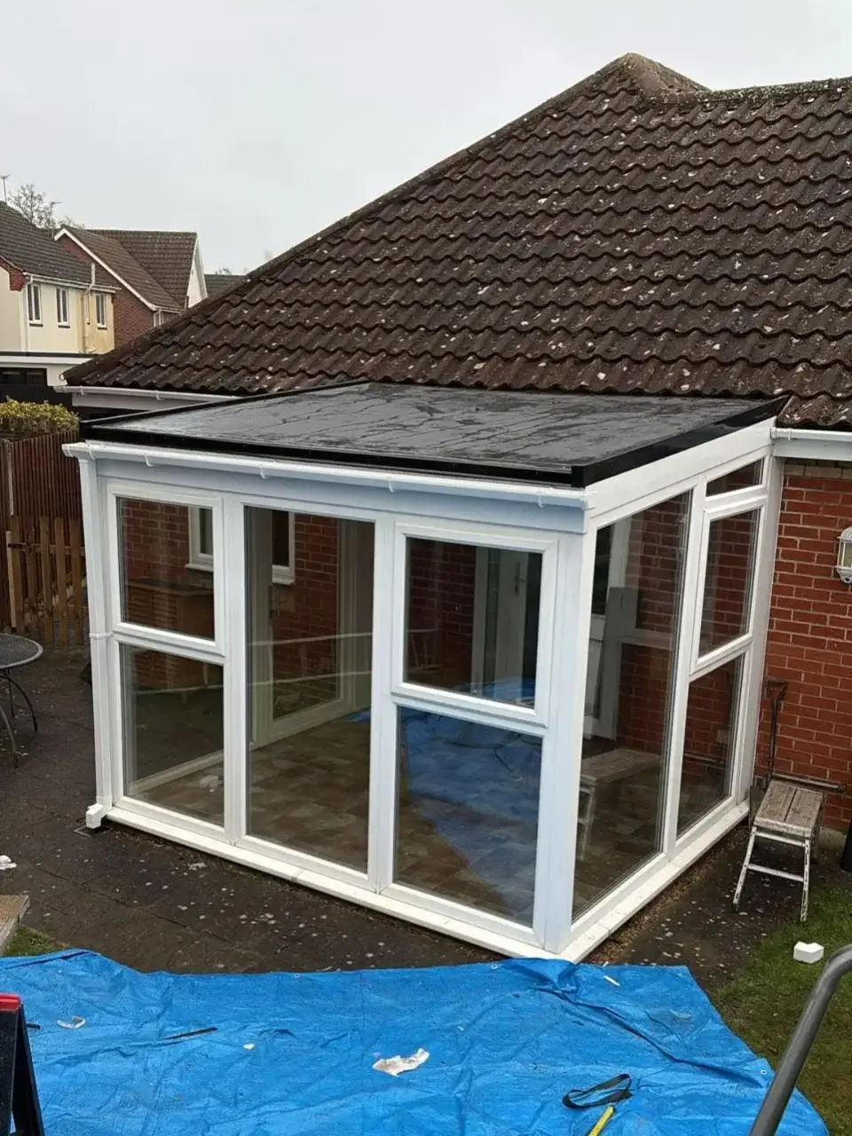Finished white uPVC Victorian conservatory featuring a high-performance tiled roof system and modern patio flags. By Norfolk Exterior Solutions
